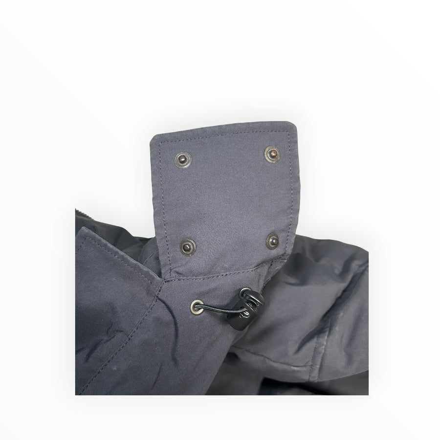 Détail de la patte de boutonnage et cordon de serrage sur une parka noire Secondstore Canada Goose