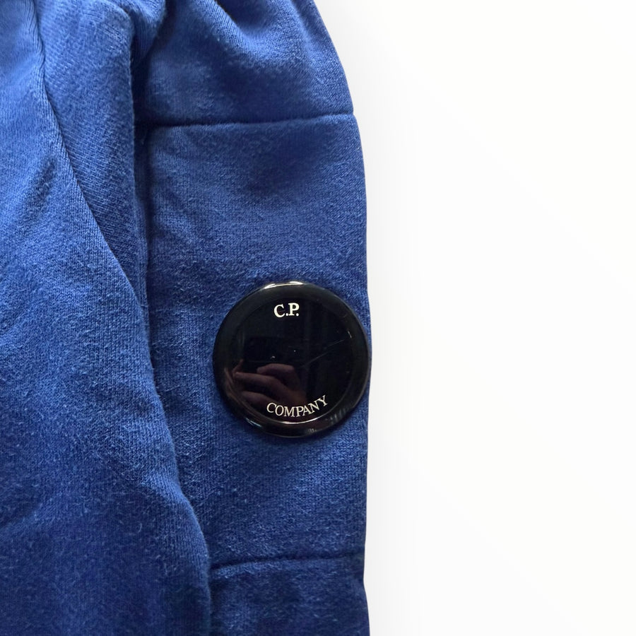 Détail de la manche d'un sweat-shirt bleu Secondstore C.P. COMPANY avec la lentille iconique noire sur poche zippée