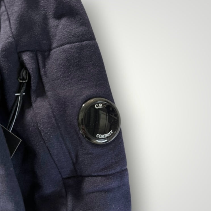 Détail de la manche d'un sweat-shirt Secondstore C.P. Company bleu marine avec sa poche zippée et sa lentille iconique