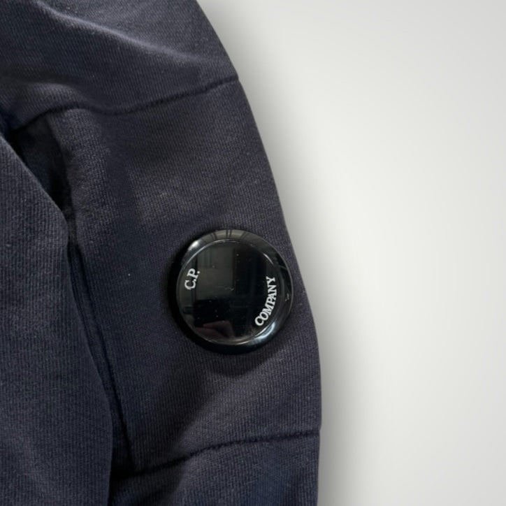 Détail de la manche d'un sweat-shirt Secondstore C.P. COMPANY bleu marine avec la lentille signature noire