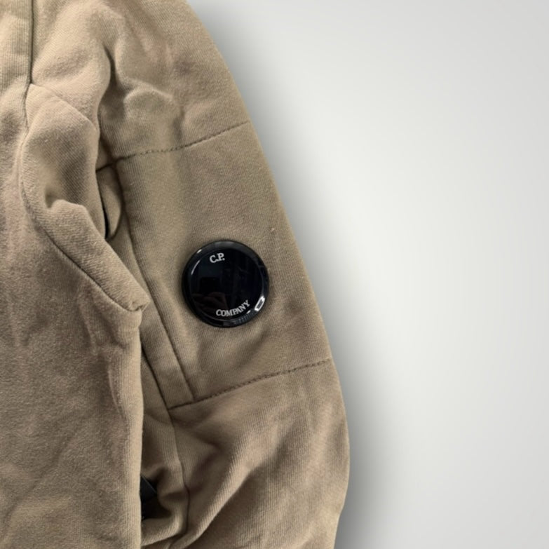 Détail de la manche beige d'un sweat-shirt Secondstore C.P. Company avec la lentille emblématique sur poche zippée