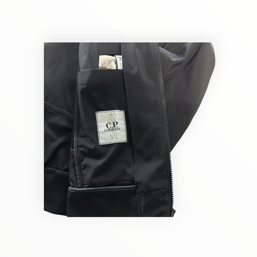 Détail intérieur de la veste noire Secondstore C.P. Company Shell-R avec étiquette de marque et fermeture éclair