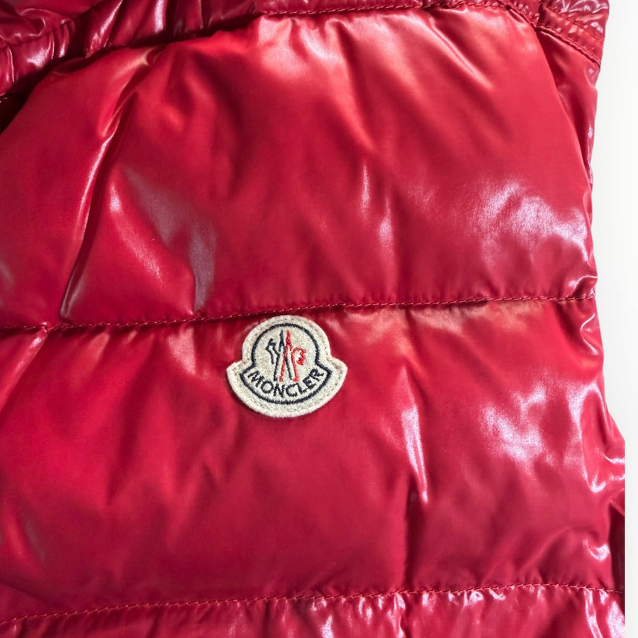 Gros plan sur le logo brodé Moncler sur une doudoune sans manches rouge vif brillante chez Secondstore