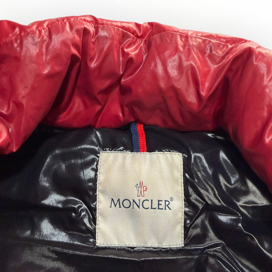 Gros plan sur l'étiquette intérieure et le col rouge brillant d'un gilet sans manches Moncler chez Secondstore