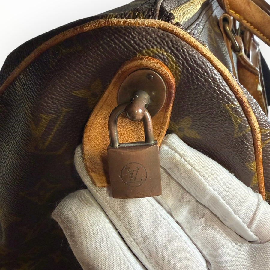 Cadenas en laiton gravé sur sac de voyage Secondstore Louis Vuitton Keepall en toile Monogram et cuir patiné