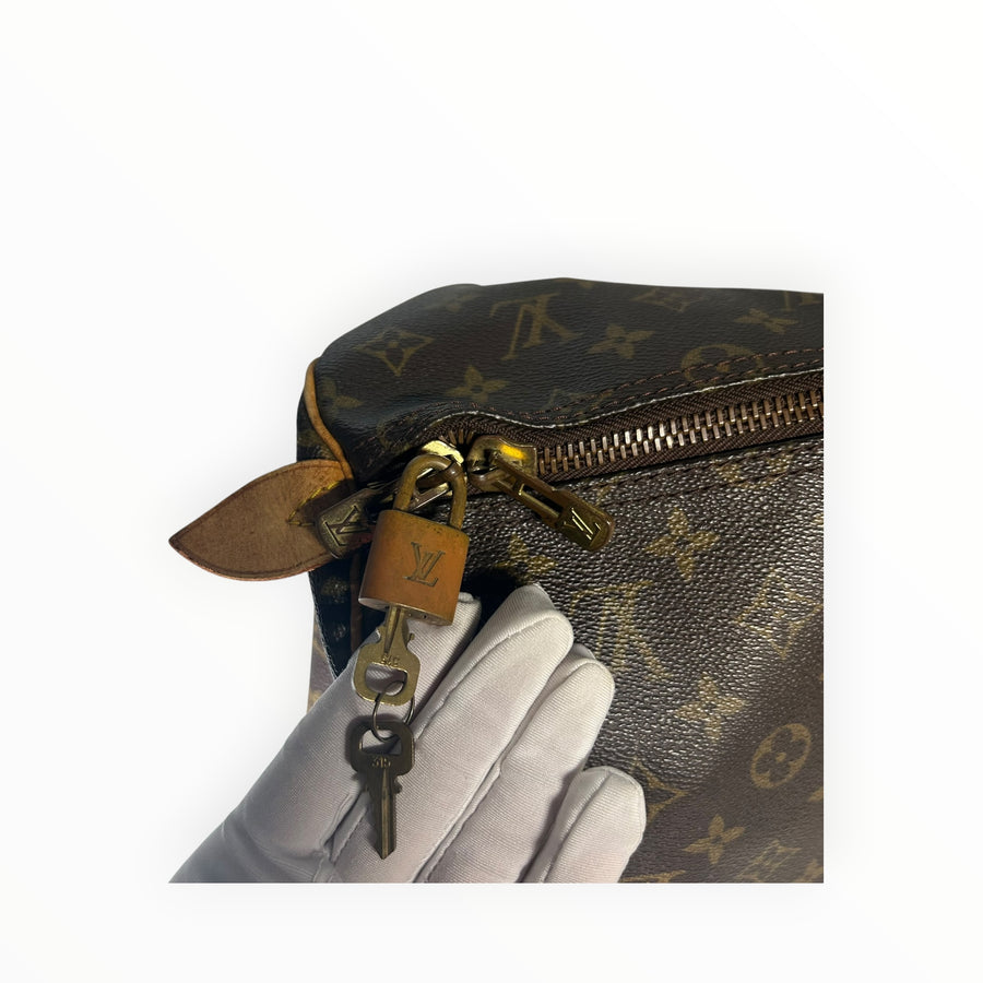 Détail du cadenas et de la fermeture éclair dorée sur un sac de voyage Secondstore Louis Vuitton Keepall en toile Monogram