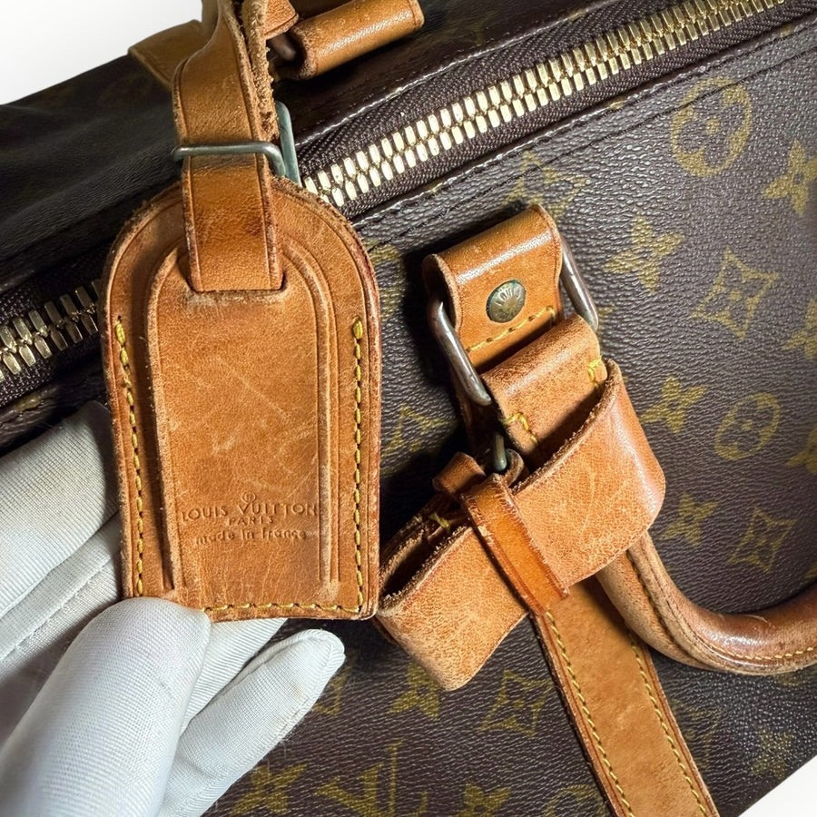 Détail du sac de voyage Secondstore Louis Vuitton Keepall en toile Monogram avec étiquette en cuir patiné