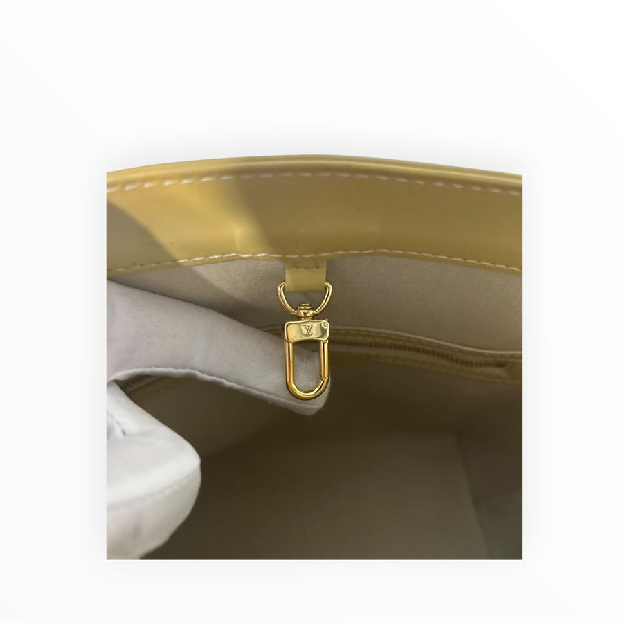 Détail du fermoir mousqueton doré à l'intérieur du sac cabas Secondstore Louis Vuitton en cuir verni jaune pâle