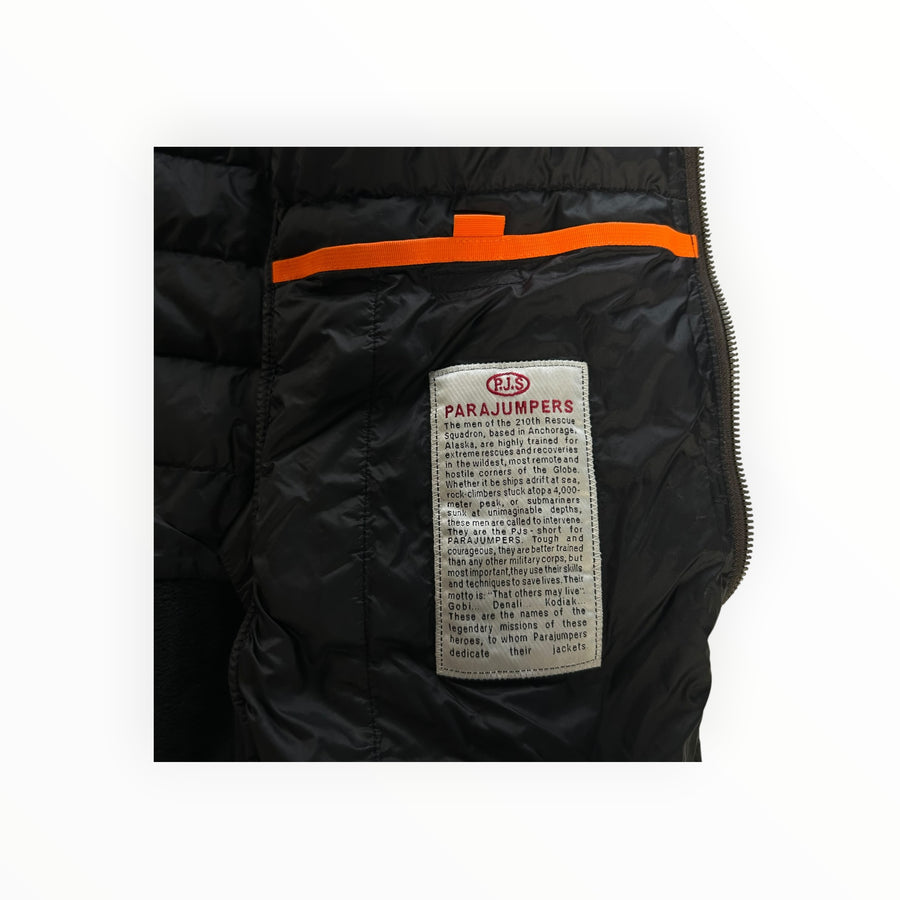 Interior detail of a black Secondstore Parajumpers hybrid jacket showing the signature narrative patch and orange trim