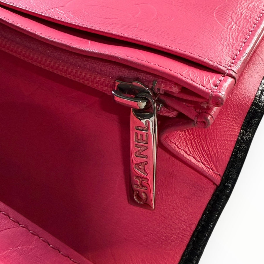Détail de la tirette en métal gravée Chanel sur l'intérieur en cuir rose vif d'un portefeuille Secondstore