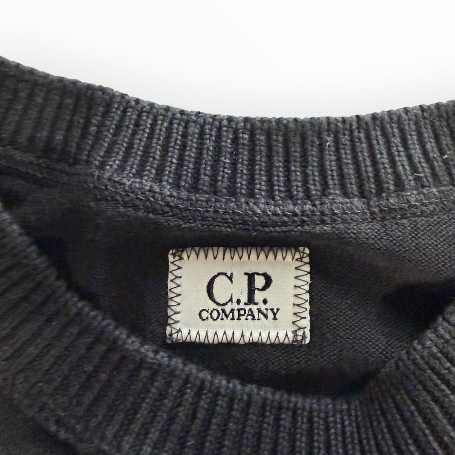 Gros plan sur l'étiquette de marque C.P. Company cousue sur le col rond noir en coton d'un pull Secondstore