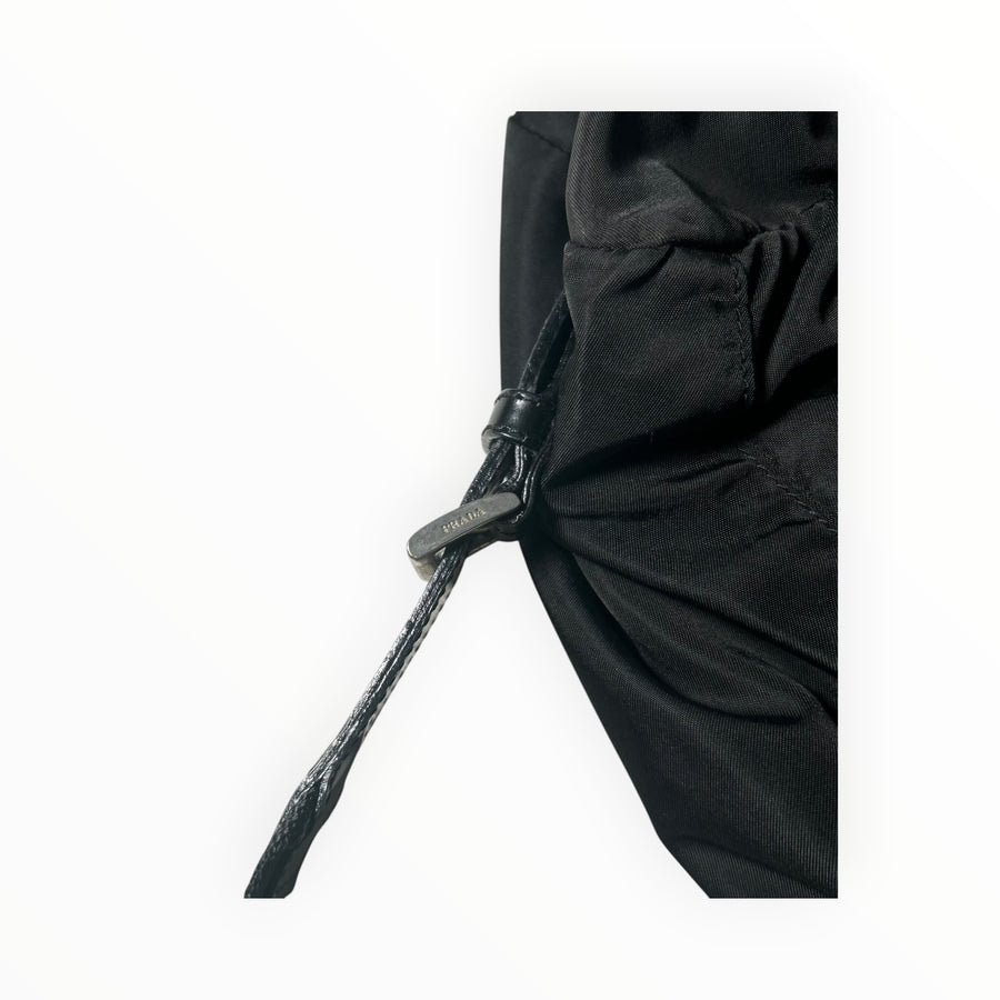 Détail du cordon de serrage en nylon noir avec embout gravé Prada sur un sac à dos Secondstore