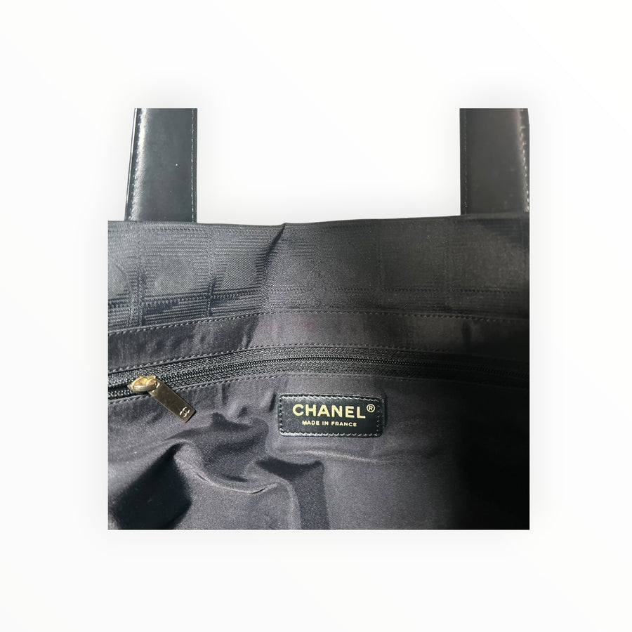 Intérieur du sac cabas Secondstore CHANEL en toile noire avec logo doré et poche zippée