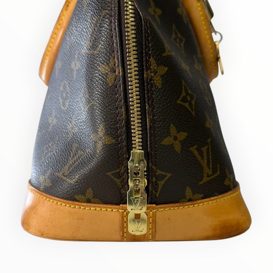 Détail de la fermeture éclair dorée et de la toile Monogram marron du sac à main Louis Vuitton Alma chez Secondstore