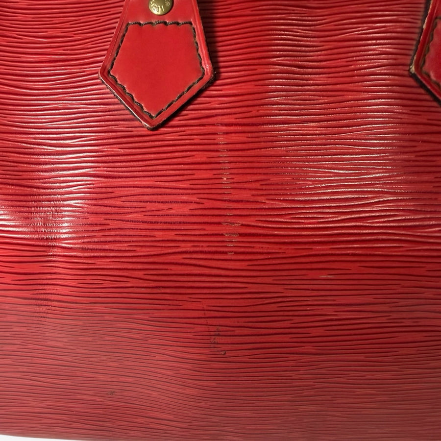 Gros plan sur le cuir Épi rouge texturé d'un sac Louis Vuitton Speedy chez Secondstore avec détails en laiton doré