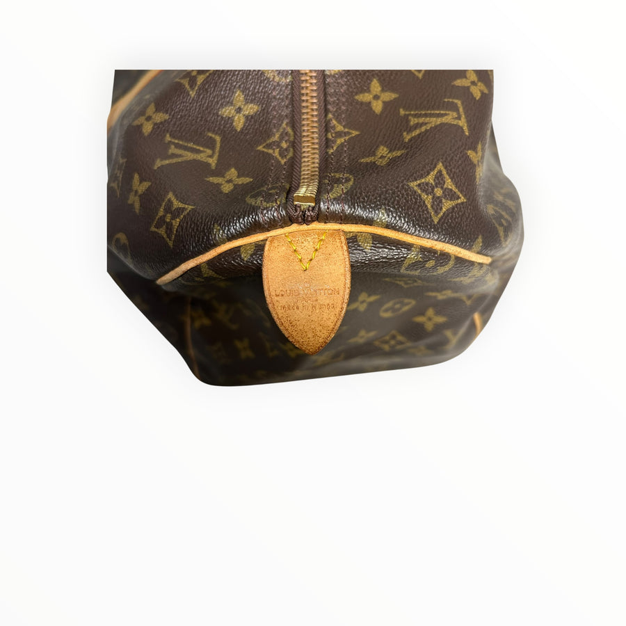 Détail de la languette en cuir Secondstore sur un sac de voyage Louis Vuitton Keepall en toile Monogram marron