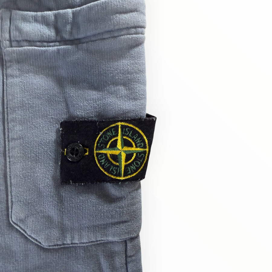 Gros plan sur le badge boussole emblématique Secondstore Stone Island sur un pantalon de jogging en coton gris bleuté