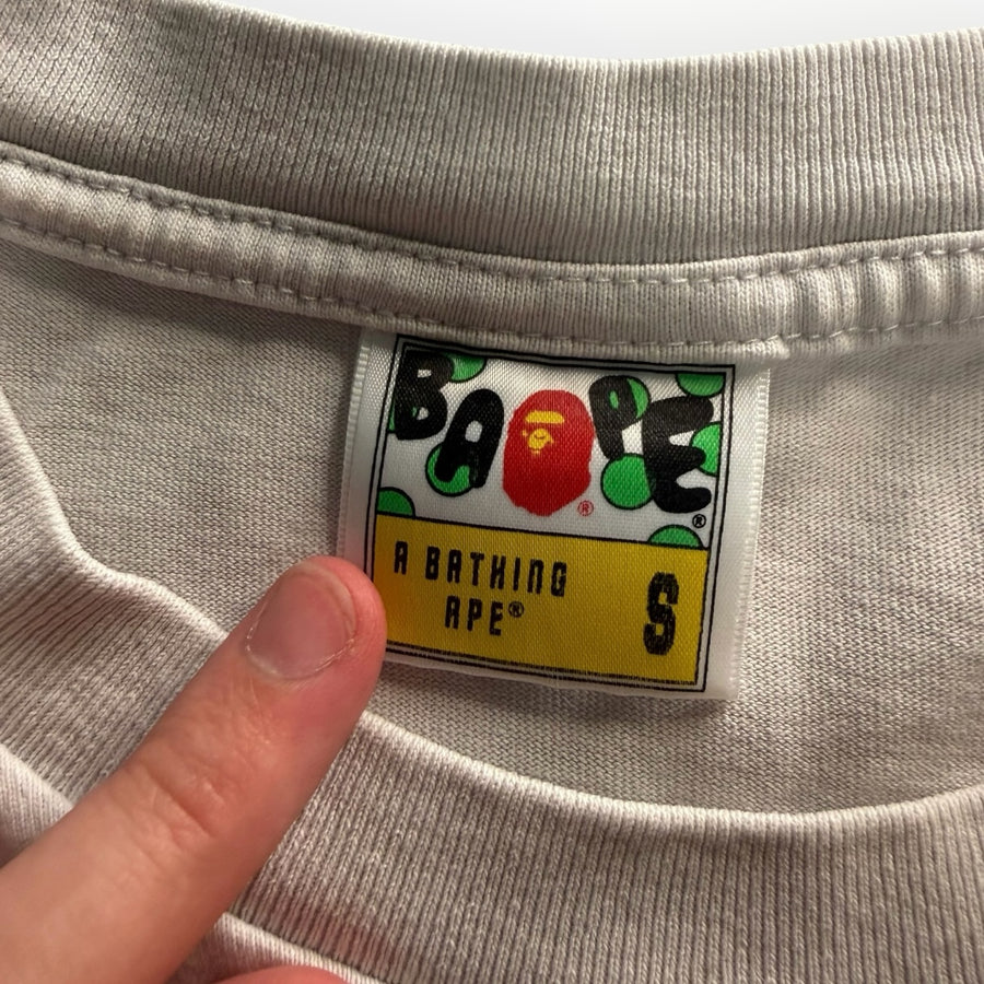 Étiquette de col Secondstore sur un t-shirt A Bathing Ape gris avec logo Ape Head coloré et taille S