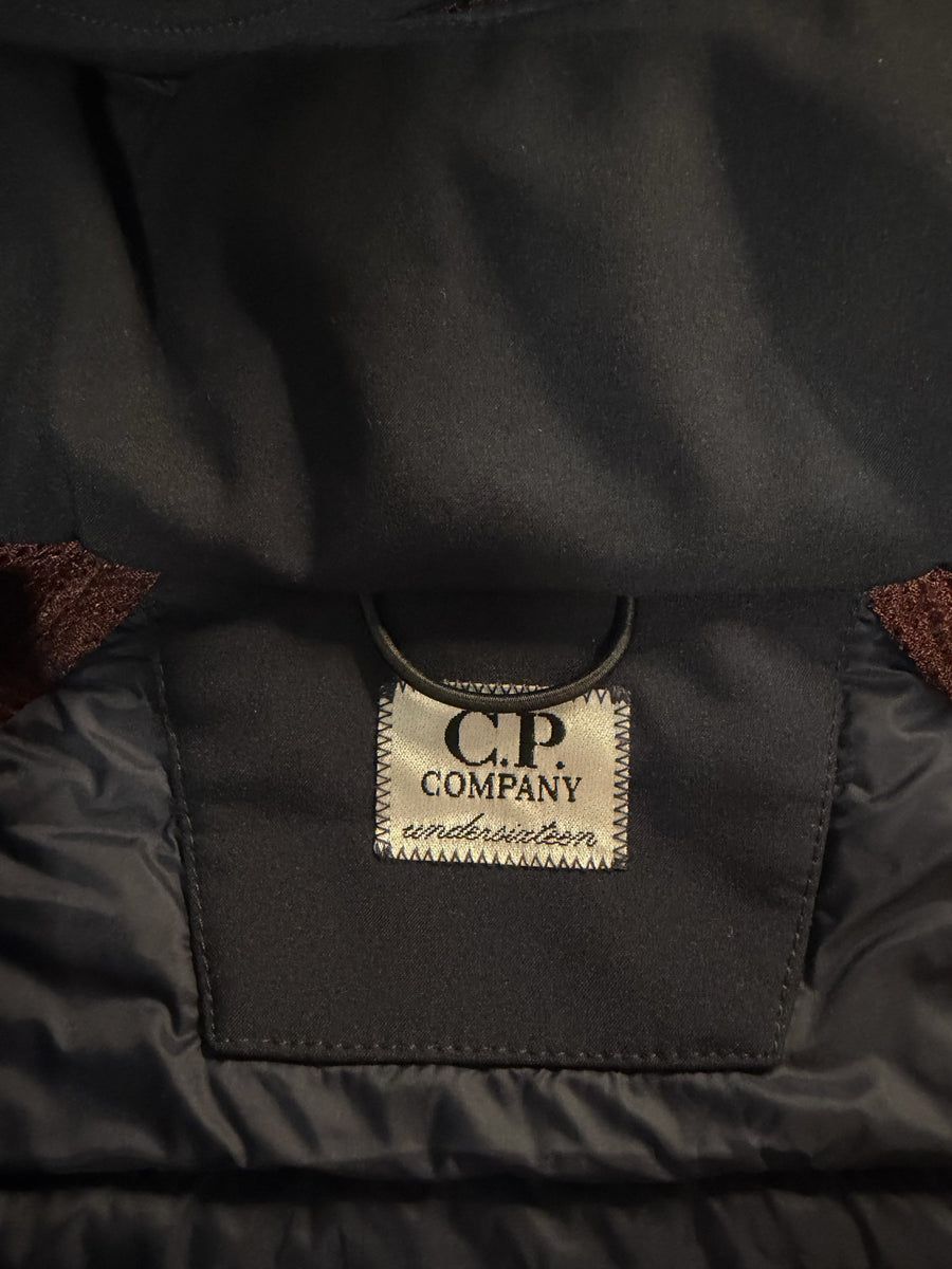 Gros plan sur l'étiquette intérieure Secondstore d'une veste C.P. Company noire avec détails matelassés