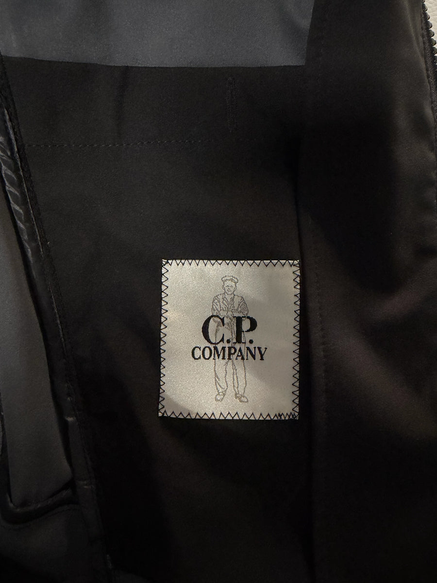 Étiquette intérieure de marque Secondstore sur une veste technique noire C.P. Company avec logo brodé