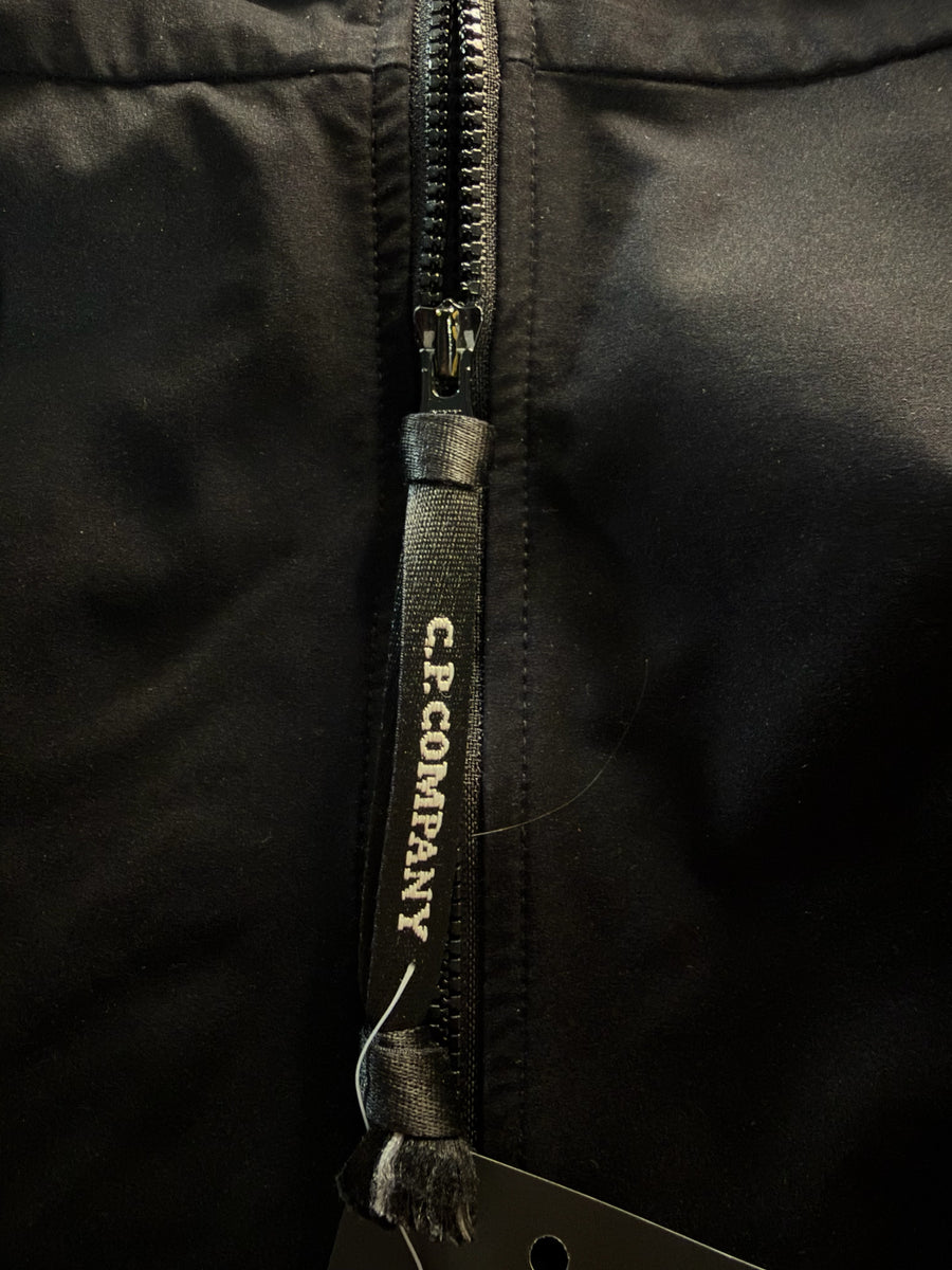 Gros plan sur la tirette de fermeture éclair noire marquée C.P. Company sur une veste technique Secondstore