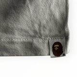 Gros plan sur l'étiquette tissée Ape Head sur la manche d'un t-shirt Secondstore A BATHING APE en coton gris