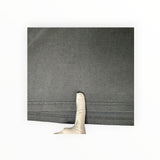 Secondstore black cotton t-shirt hem detail showing a small fabric imperfection for quality inspection