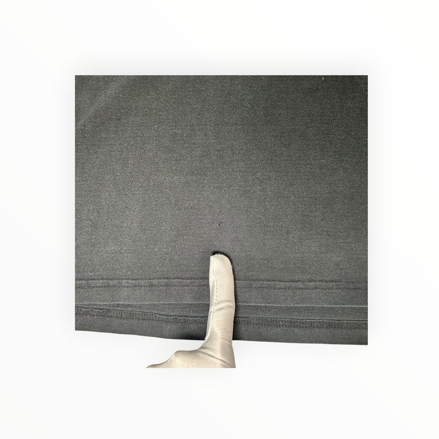 Secondstore black cotton t-shirt hem detail showing a small fabric imperfection for quality inspection