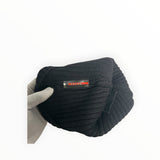 Secondstore black ribbed knit Prada beanie featuring a signature red logo plaque, held by a gloved hand.