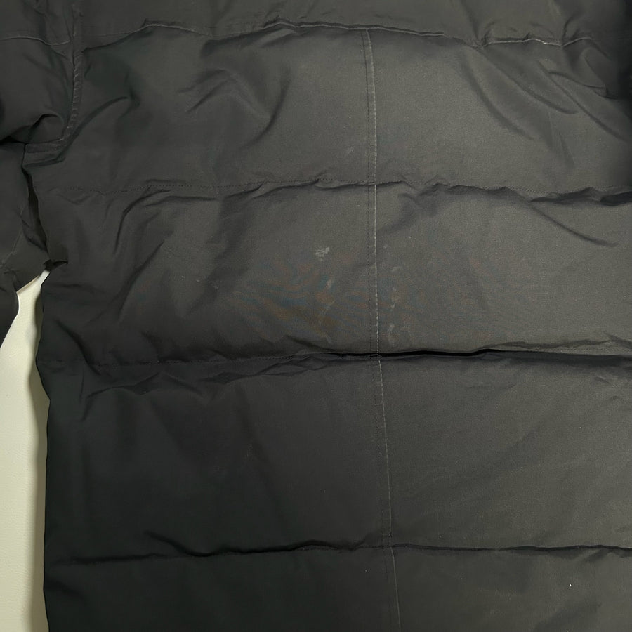 Gros plan sur le tissu matelassé noir d'une doudoune Secondstore Canada Goose avec coutures horizontales