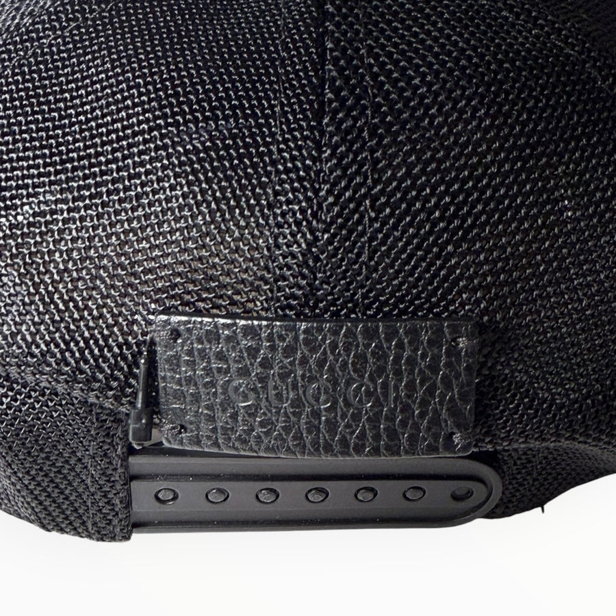 Détail de la patte de réglage en cuir embossé Gucci sur une casquette noire Secondstore en maille technique