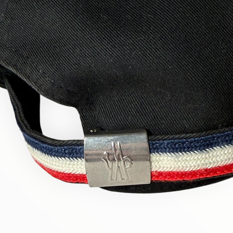 Détail de la sangle arrière Secondstore d'une casquette Moncler noire avec boucle métallique gravée et bande tricolore