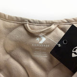 Gros plan sur l'étiquette intérieure d'une veste matelassée beige Secondstore Converse avec logo et taille L