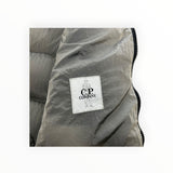 Détail de l'étiquette de marque C.P. Company sur une doudoune sans manches Secondstore en nylon irisé gris