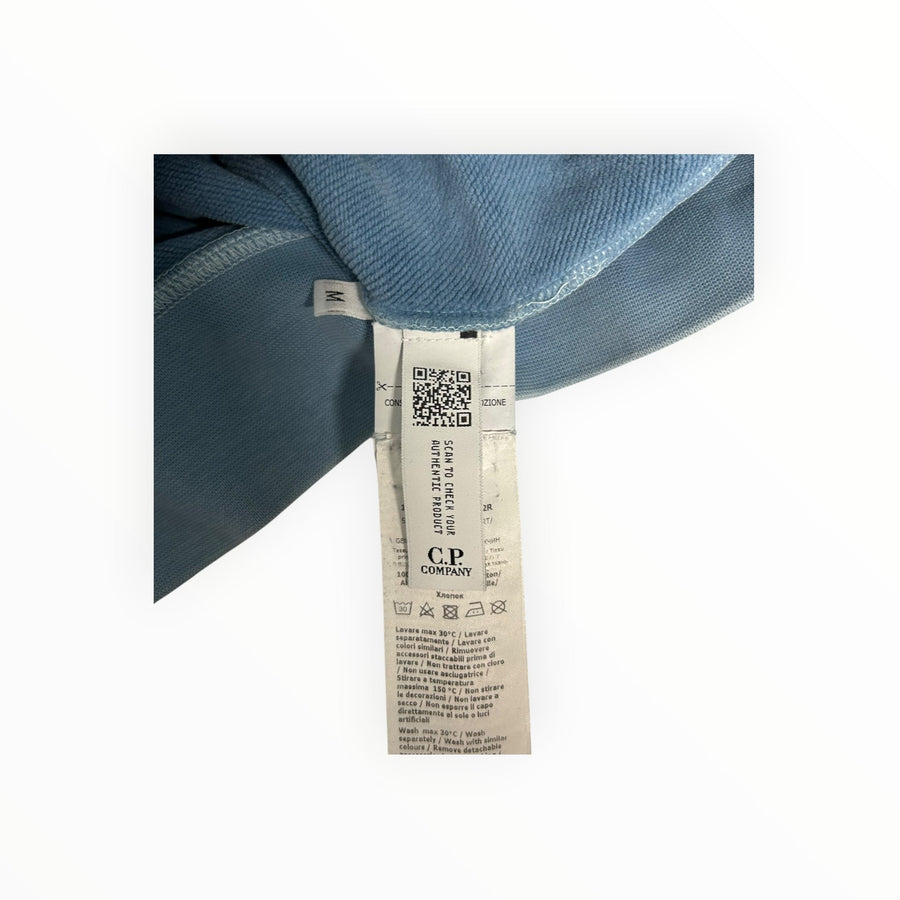 Étiquette intérieure d'authenticité Secondstore sur un sweat-shirt bleu C.P. Company avec code QR et instructions