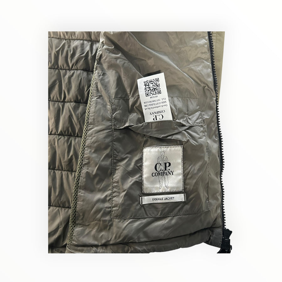 Interior of Secondstore C.P. Company Goggle Jacket showing quilted olive lining, authenticity label, and QR code tag.