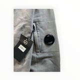 Secondstore C.P. Company grey cotton sweatshirt sleeve featuring the iconic black lens pocket detail and brand tag.