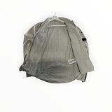 Secondstore light grey C.P. Company zip-up overshirt with iconic sleeve lens detail, shown open on a hanger.