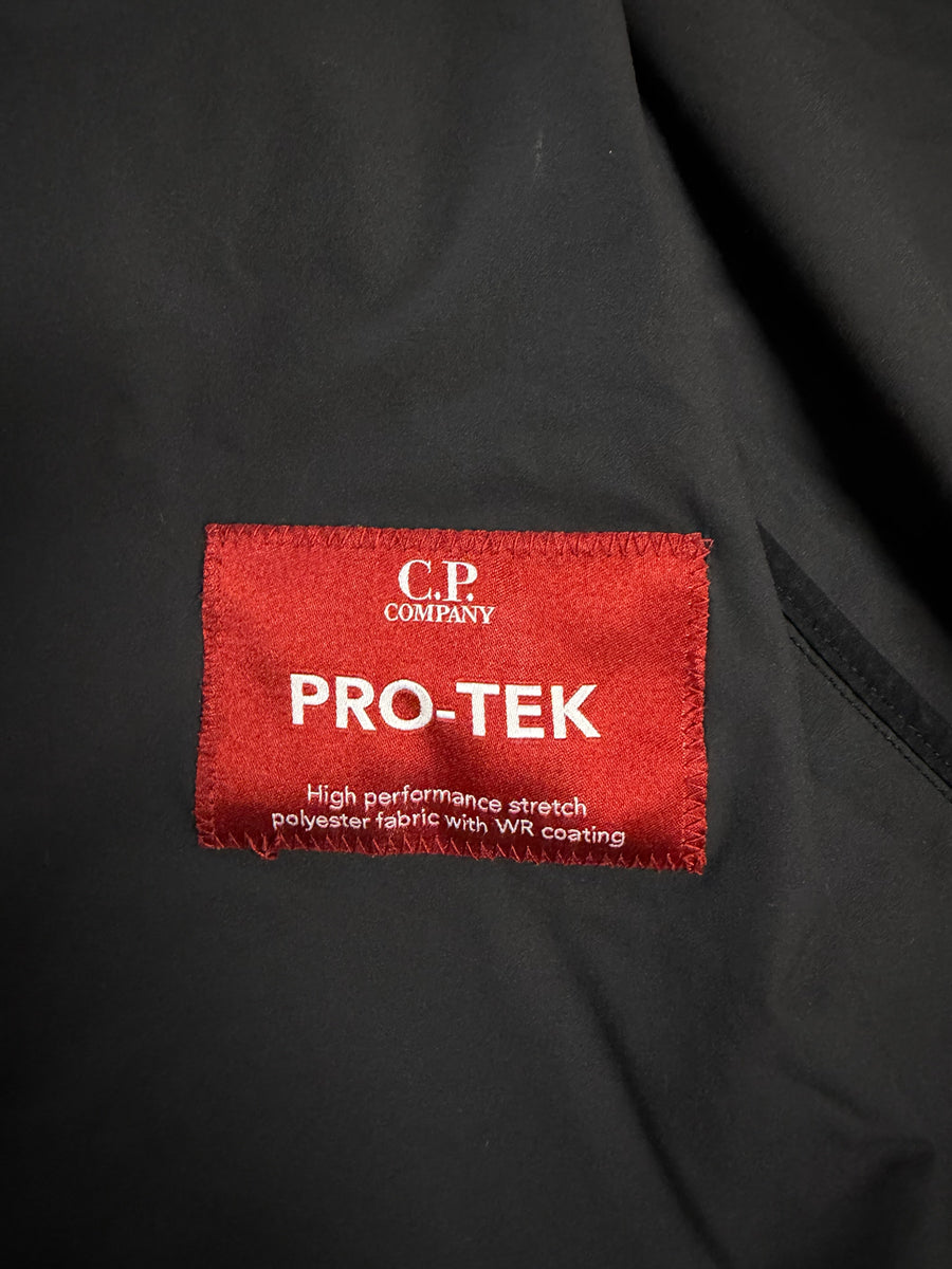 Étiquette intérieure rouge Secondstore C.P. Company Pro-Tek sur veste technique noire en polyester stretch
