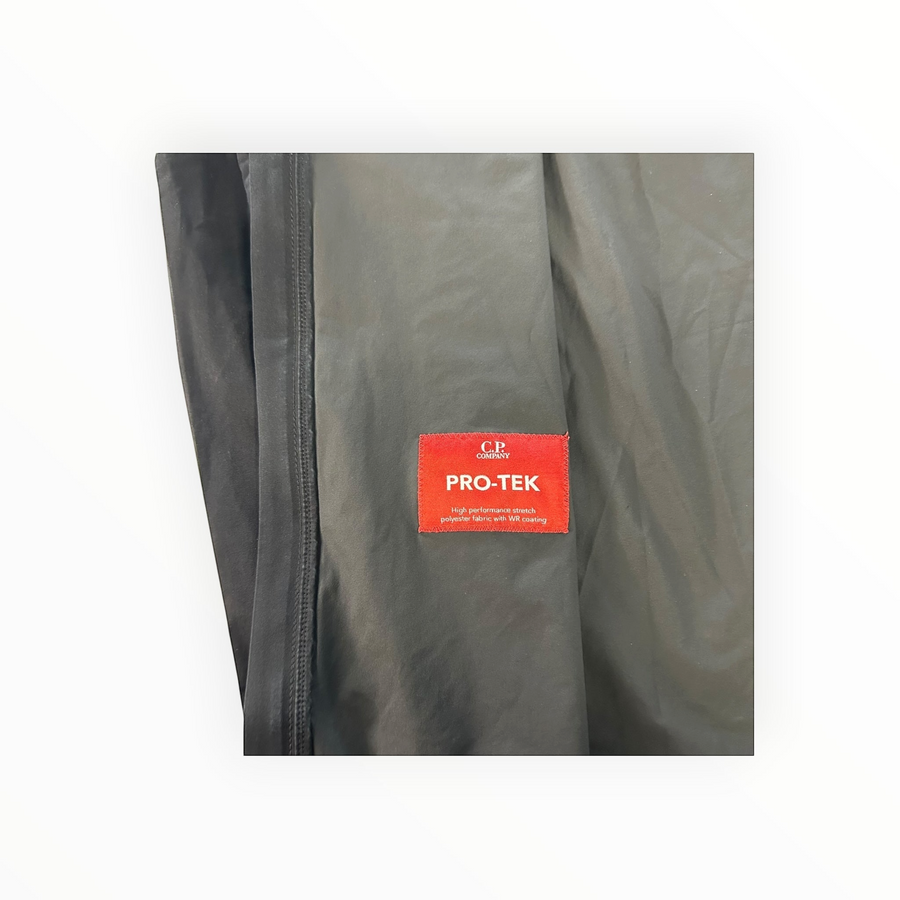 Gros plan sur l'étiquette rouge Pro-Tek d'une veste technique noire Secondstore C.P. Company en tissu stretch