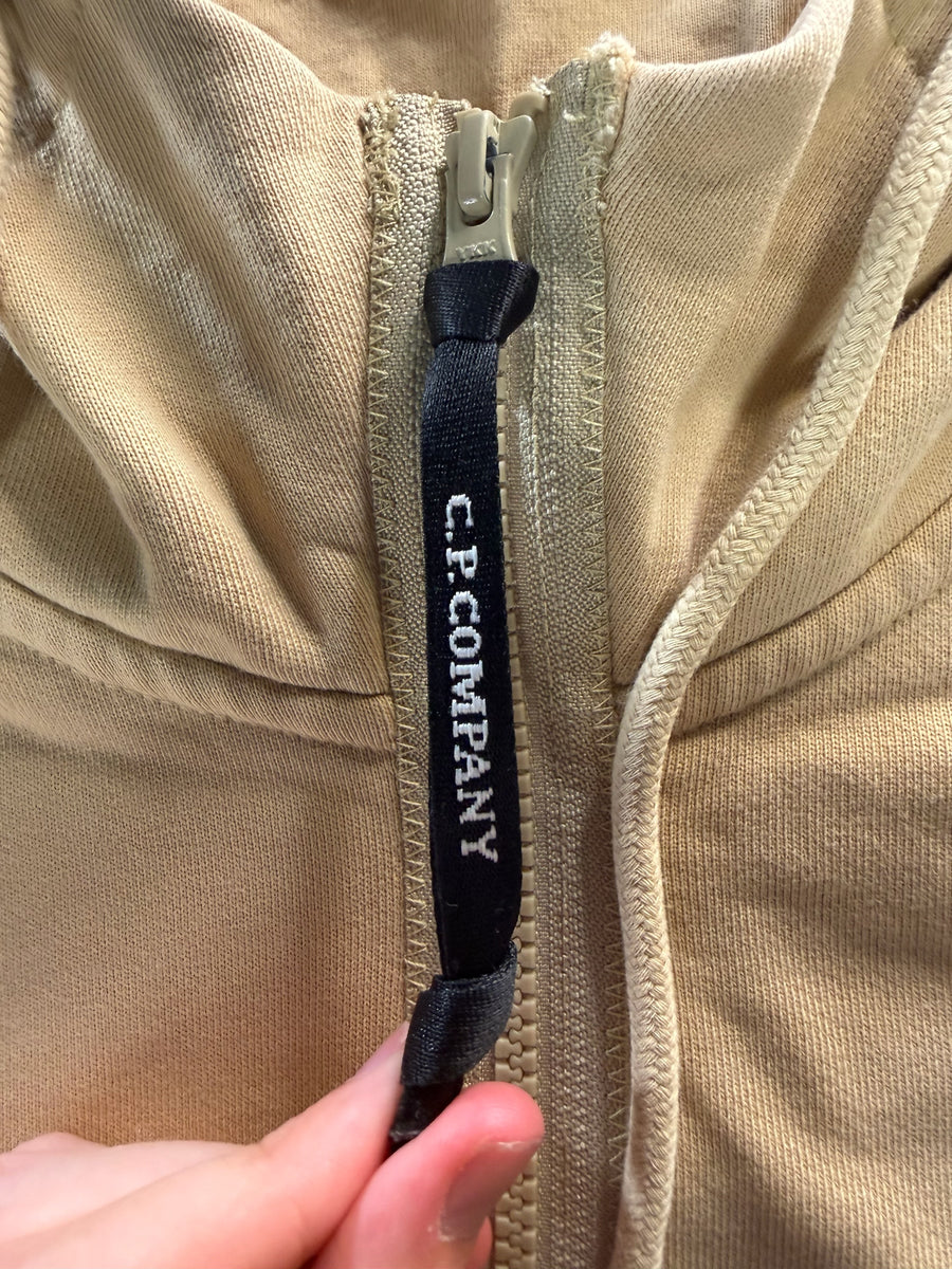 Gros plan sur la tirette de fermeture éclair noire siglée C.P. Company sur un sweat à capuche beige Secondstore