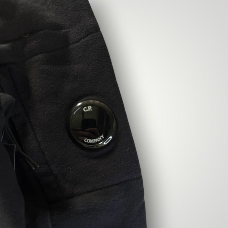 Détail de la lentille emblématique noire sur la manche d'un sweat-shirt en coton Secondstore C.P. COMPANY