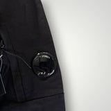 Détail de la manche noire du sweat-shirt Secondstore C.P. Company avec la lentille signature sur poche zippée