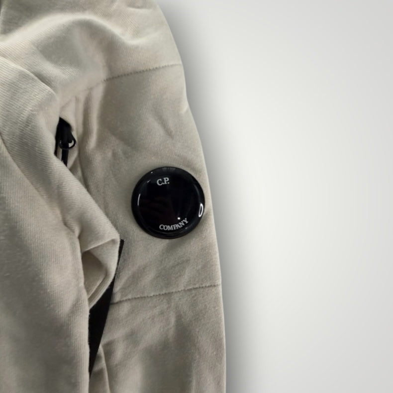 Détail de la manche beige du sweat-shirt Secondstore C.P. Company avec sa lentille emblématique sur poche zippée