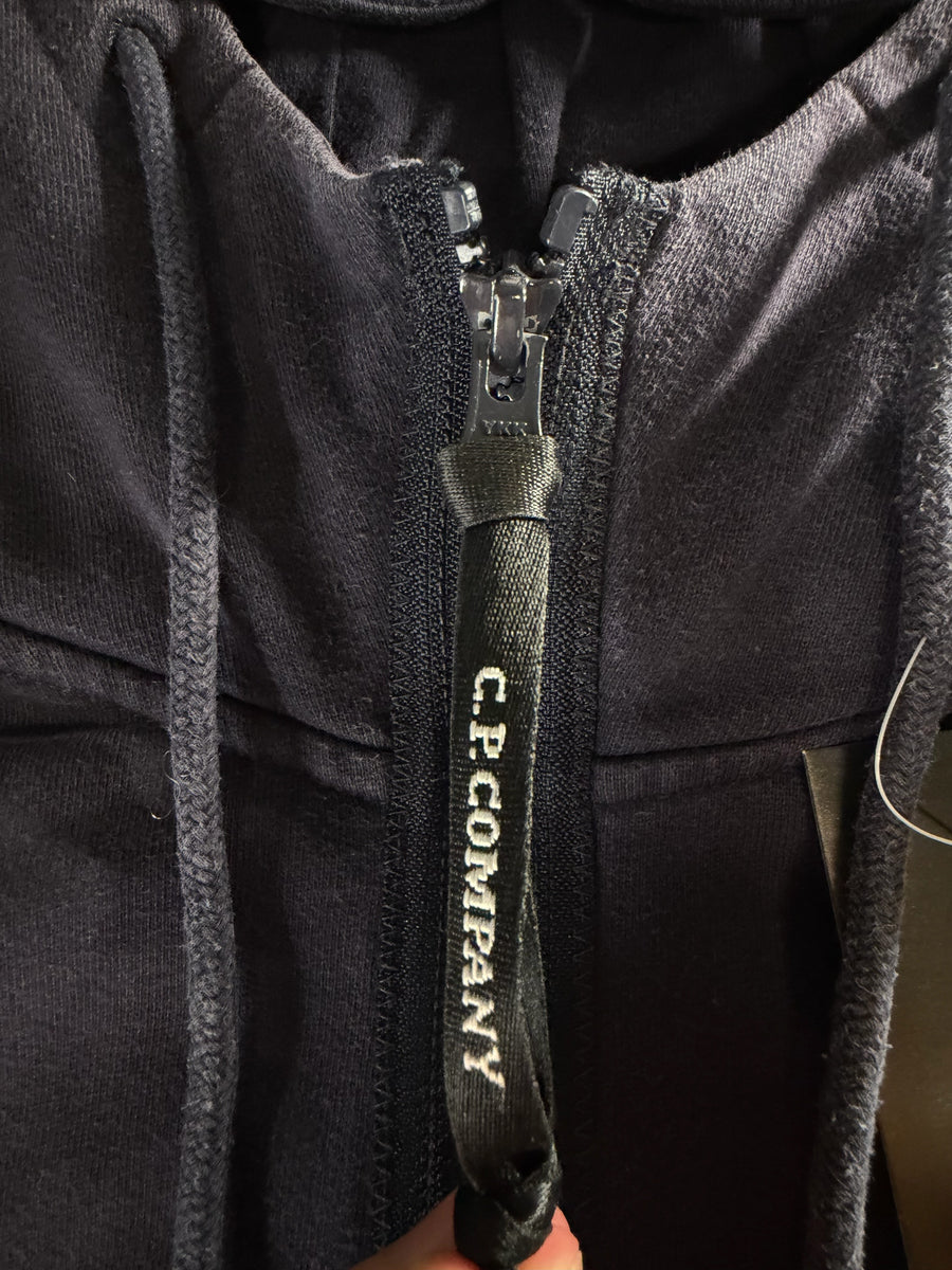 Gros plan sur la tirette zippée logotée Secondstore C.P. Company d'un sweat-shirt bleu marine en coton