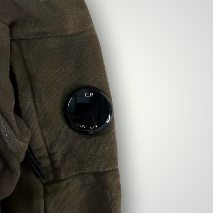 Détail de la lentille noire emblématique sur la manche d'un sweat-shirt vert olive Secondstore C.P. COMPANY