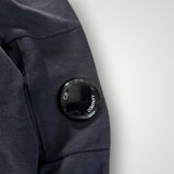 Détail de la manche d'un sweat-shirt Secondstore C.P. COMPANY bleu marine avec la lentille signature noire