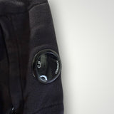 Gros plan sur la lentille emblématique noire sur la manche d'un sweat-shirt Secondstore C.P. COMPANY en coton