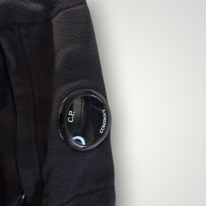 Gros plan sur la lentille emblématique noire sur la manche d'un sweat-shirt Secondstore C.P. COMPANY en coton
