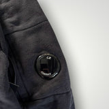 Détail de la manche d'un sweat-shirt noir Secondstore C.P. COMPANY avec la lentille emblématique sur la poche
